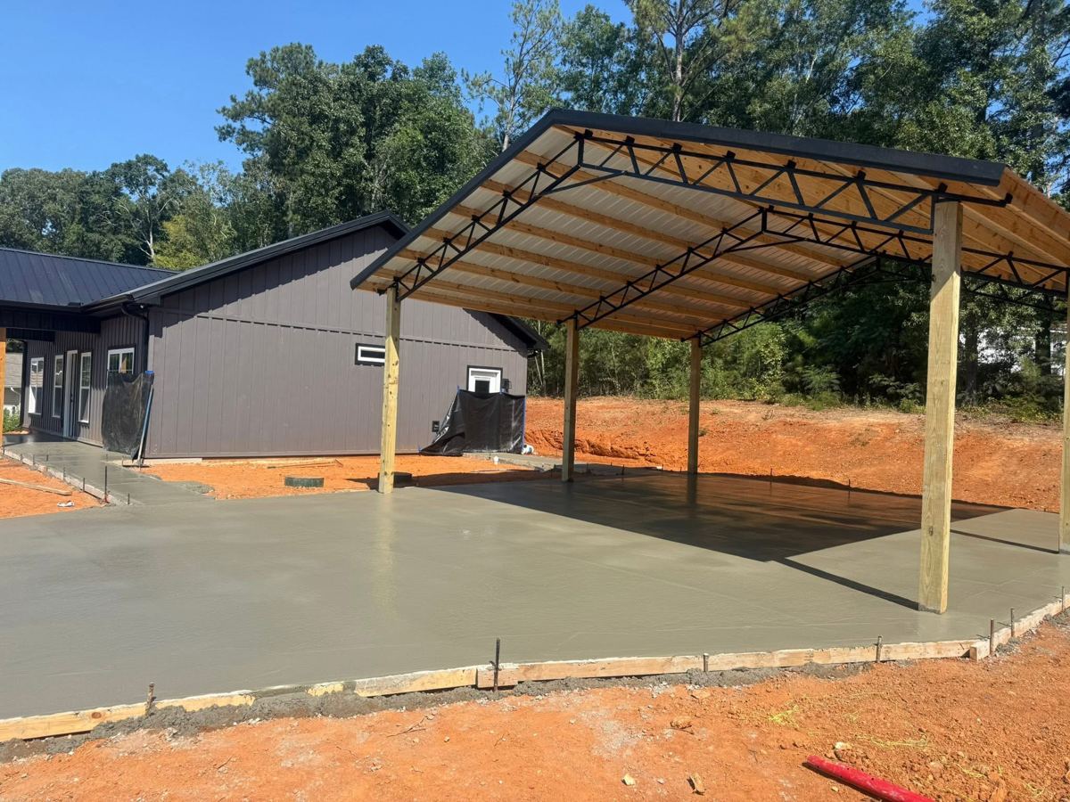 A fresh slab under a new carport beside a house